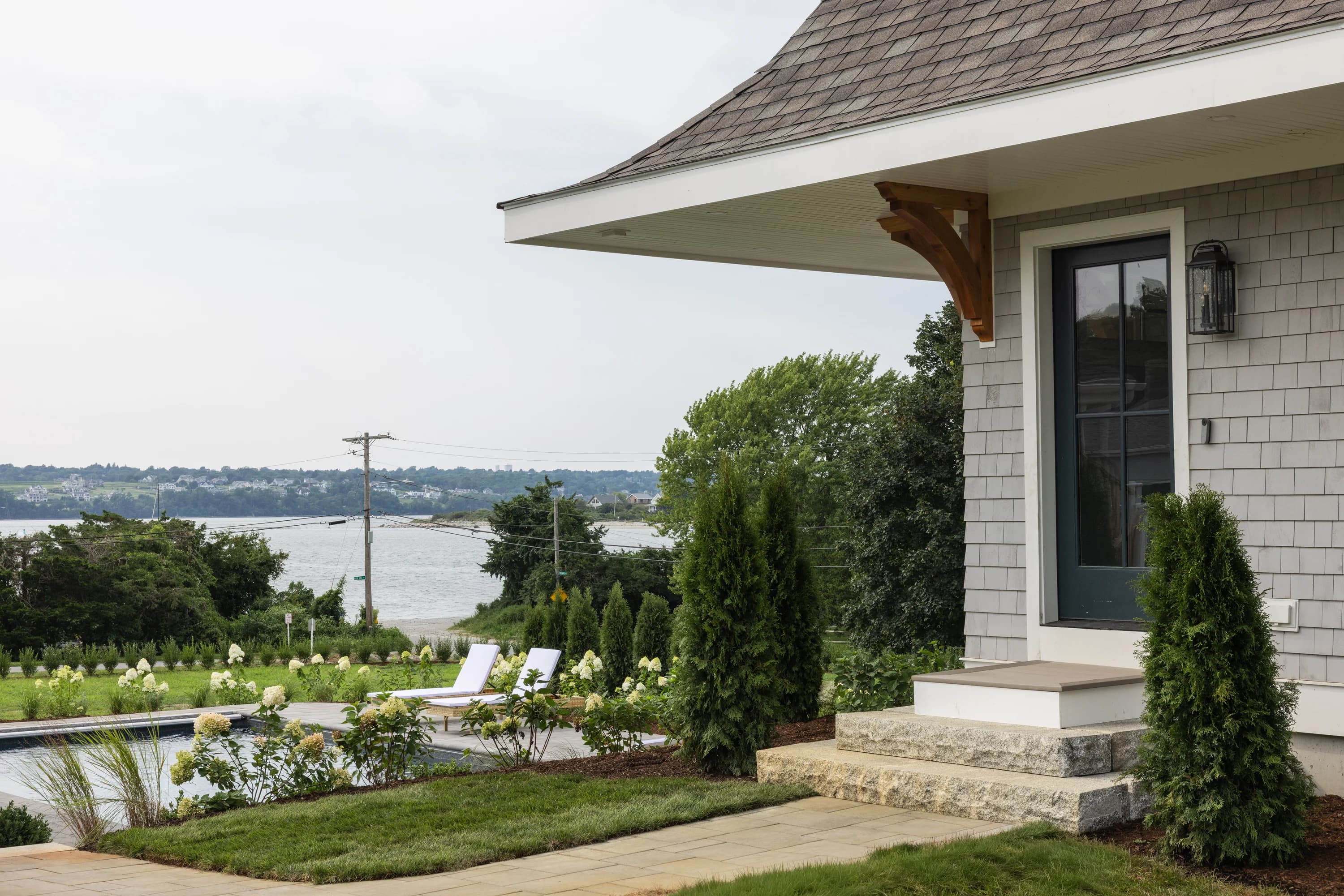 Side entrance and stone patio at Project One Zero Eight, a coastal shingle home in Narragansett, Rhode Island