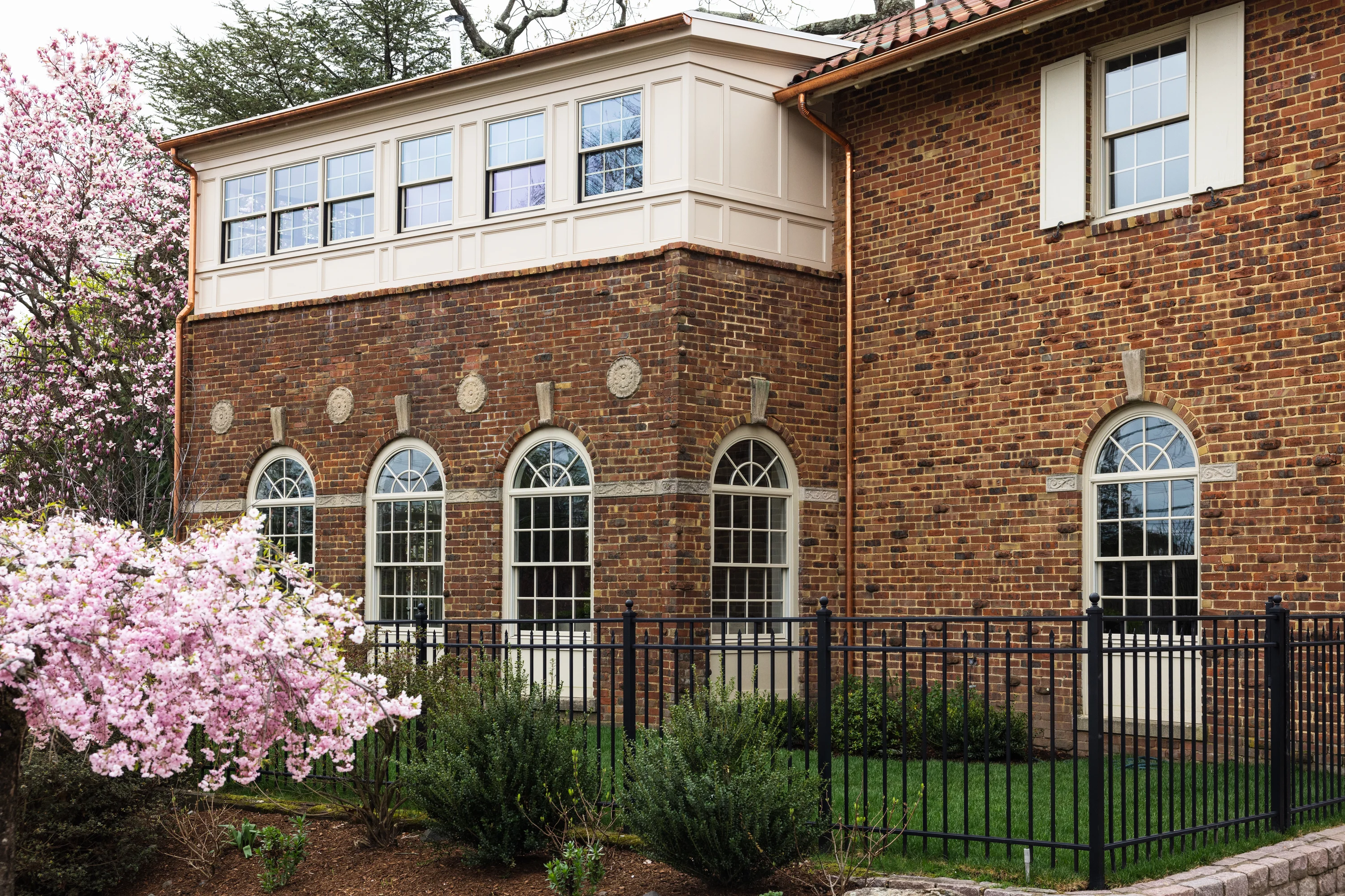 Project Six Twelve Spanish Revival brick exterior with arched windows and spring blossoms in Providence, Rhode Island