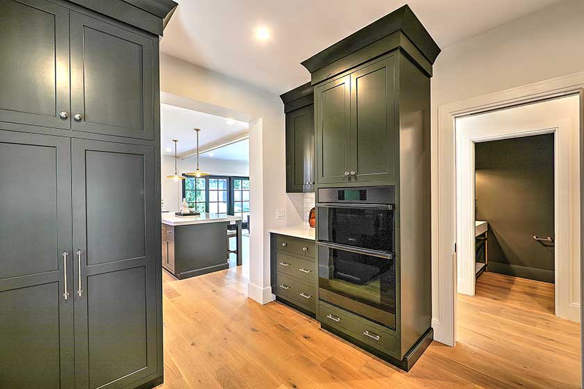 Moody and sophisticated butler's pantry featuring custom dark green floor-to-ceiling cabinetry.