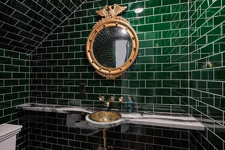 Moody and dramatic wet bar featuring emerald green gloss tiles and brass fixtures.