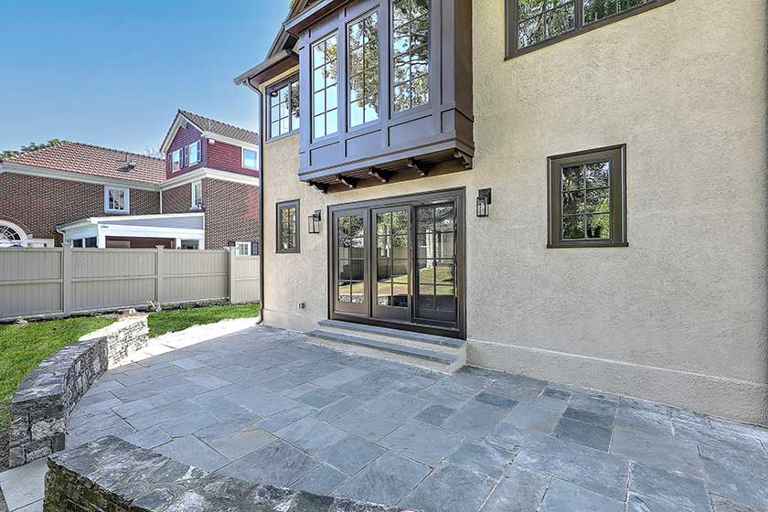 Exterior view showing how the modern addition integrates with the historic stucco facade and stone patio.