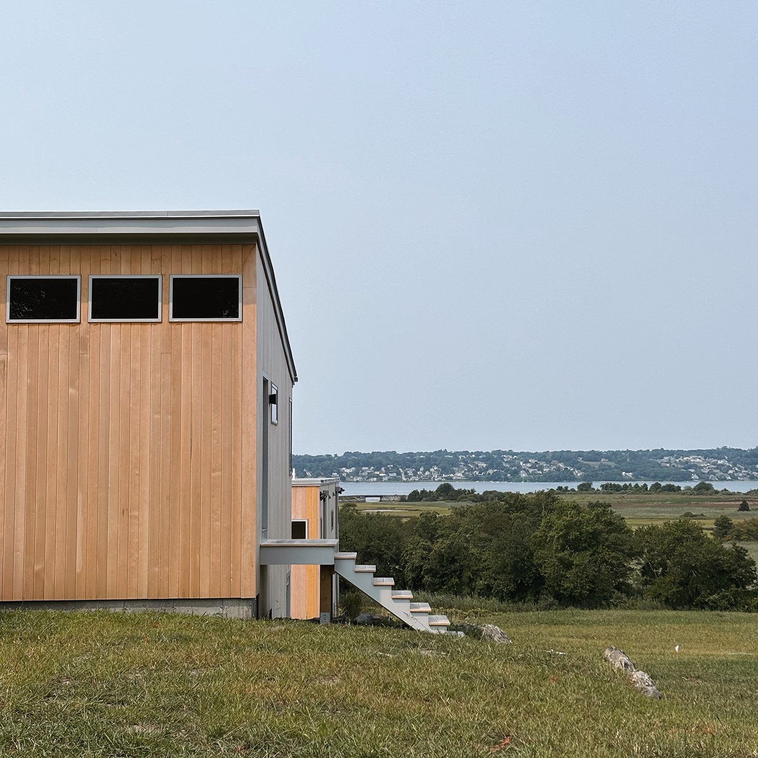 Exterior view of a modern custom coastal home overlooking the water, engineered to withstand Rhode Island weather and time