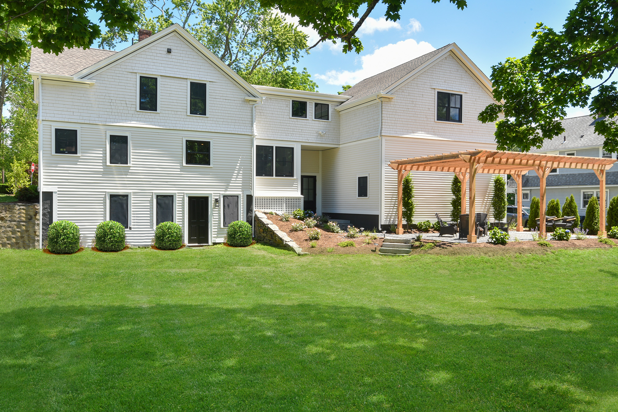 Wide view of the historic home renovation showing the new two-car garage addition and primary suite above.