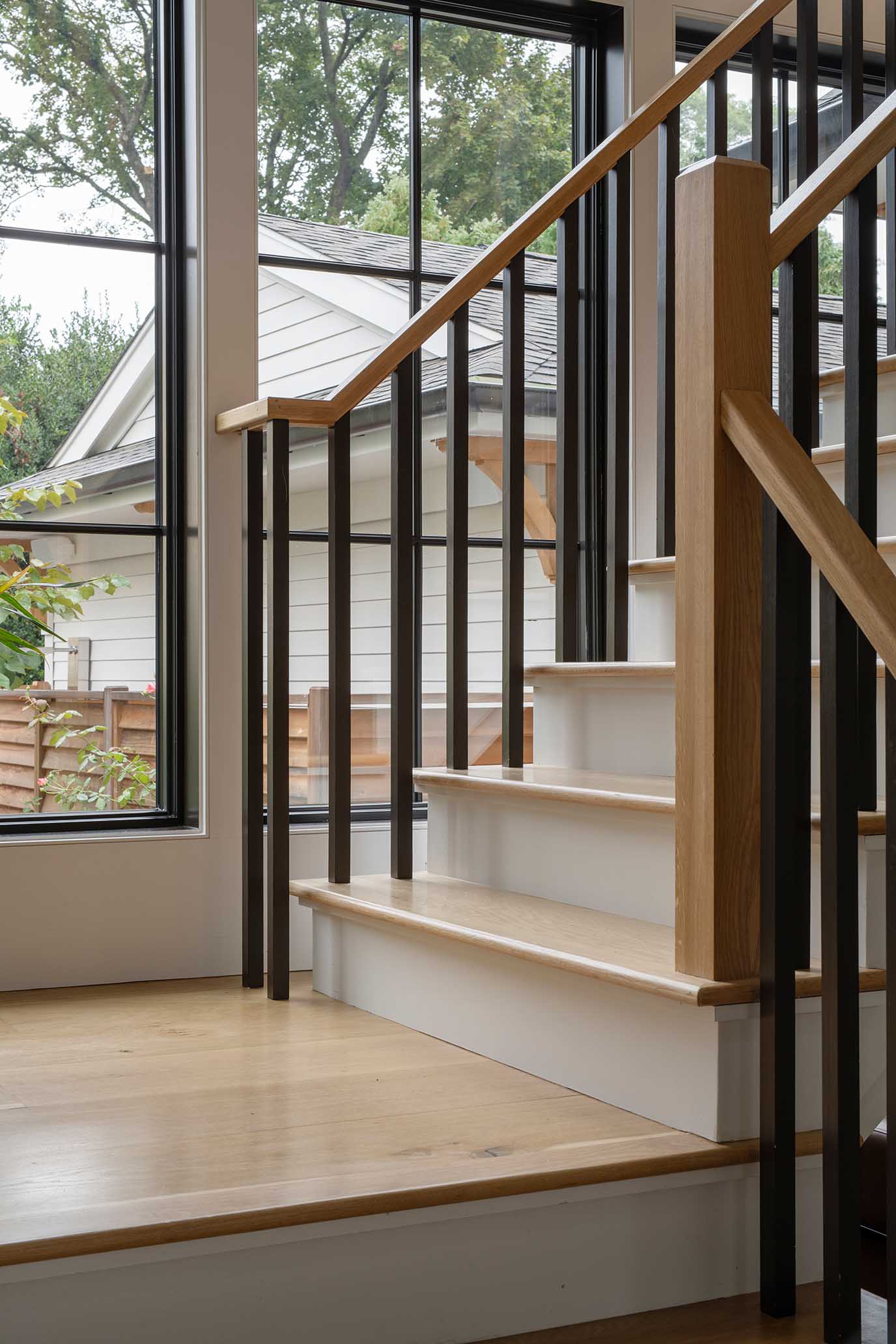 Sunlit stairwell landing with custom white oak treads, reflecting the precise execution of Rhode Island