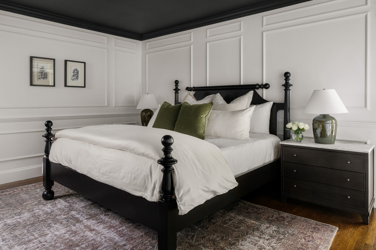 Primary bedroom with black four-poster bed, picture-frame molding and green pillows at Project Five Fourteen in Providence, Rhode Island