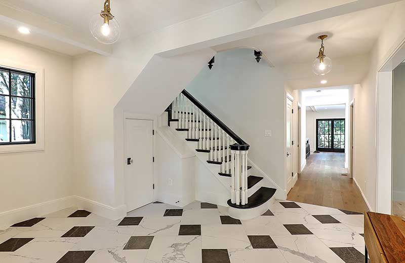 Grand foyer renovation featuring classic black and white tiles and a restored staircase.