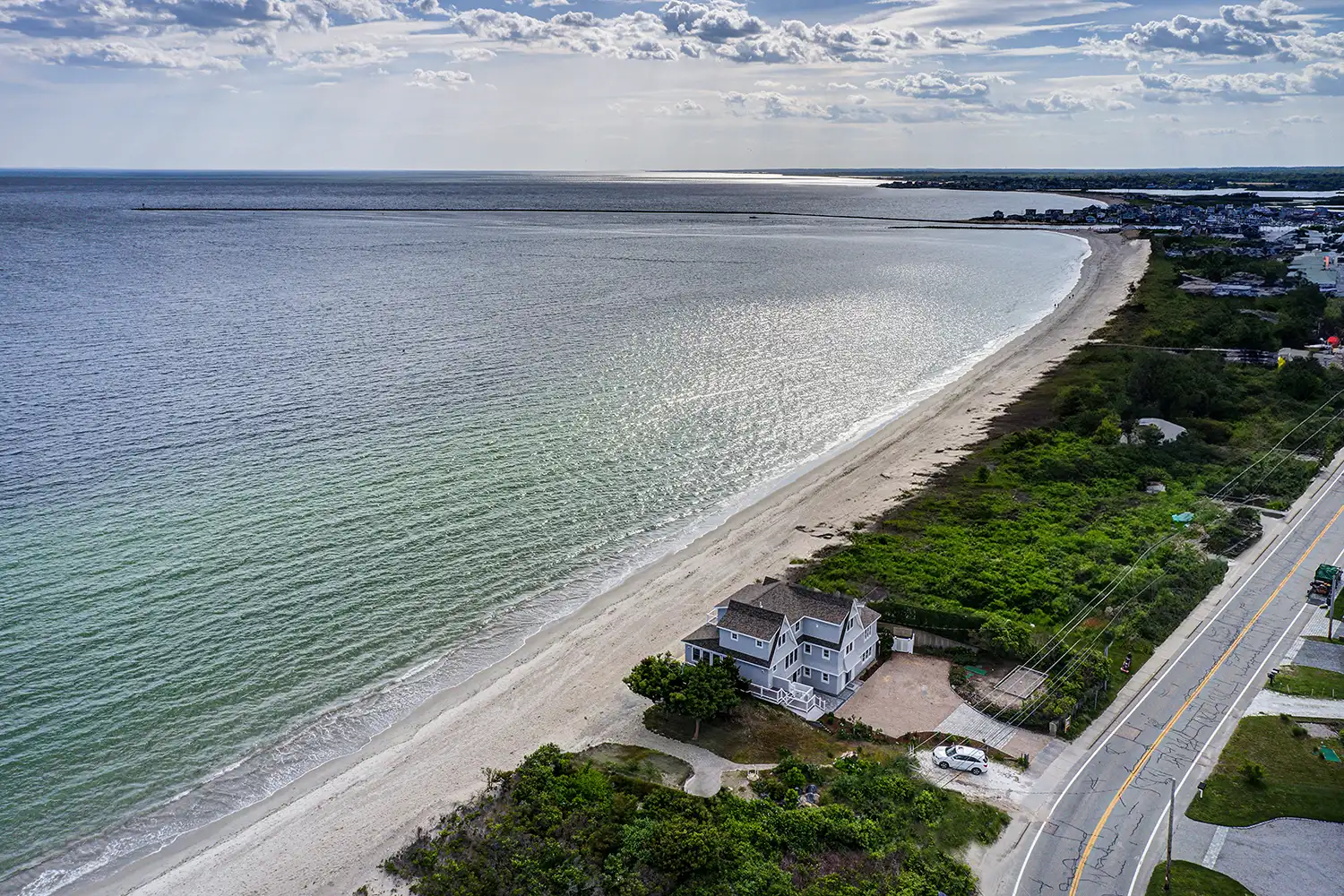 Aerial view of a luxury waterfront home renovation in Narragansett, RI, overlooking Sand Hill Cove.
