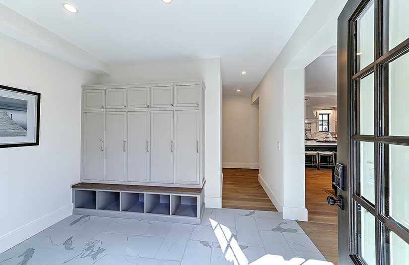 Spacious mudroom addition with custom white built-in cubbies and durable tile flooring for family life.