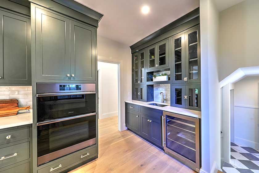 Detail of a custom wet bar with glass-front cabinetry and wine storage, adding luxury utility to the home.