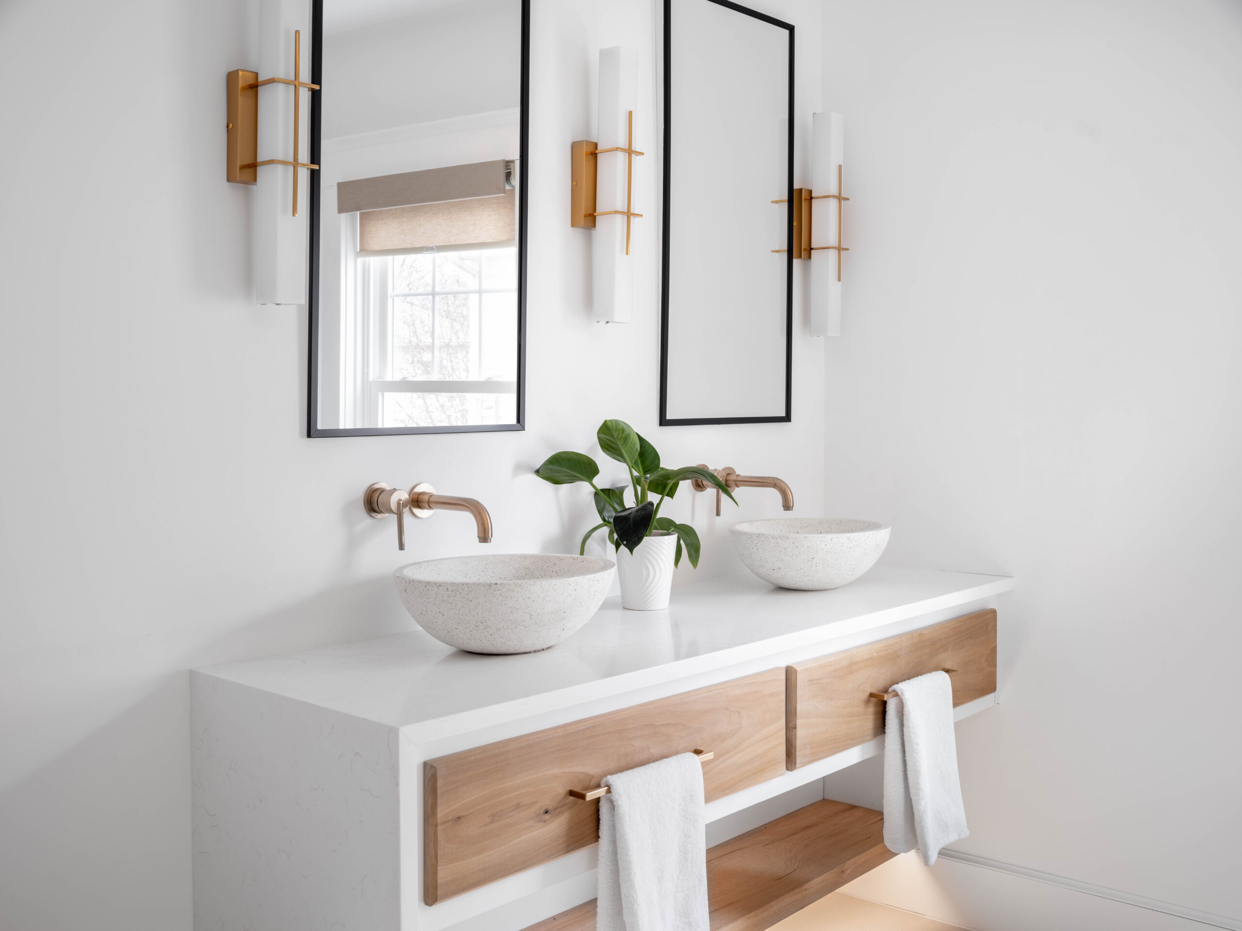 Contemporary bathroom design featuring a warm wood double vanity and minimalist wall sconces.