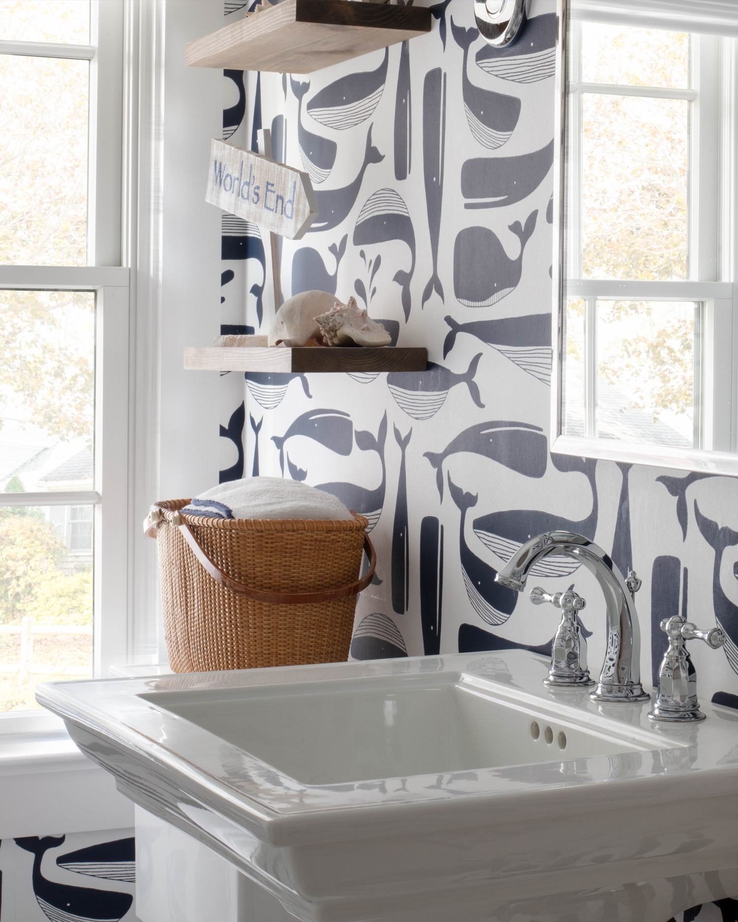Charming coastal bathroom design featuring nautical whale wallpaper and a classic pedestal sink, honoring the home's seaside location.