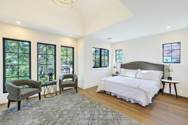 New primary bedroom suite featuring vaulted ceilings and large windows, created by a second-story addition.