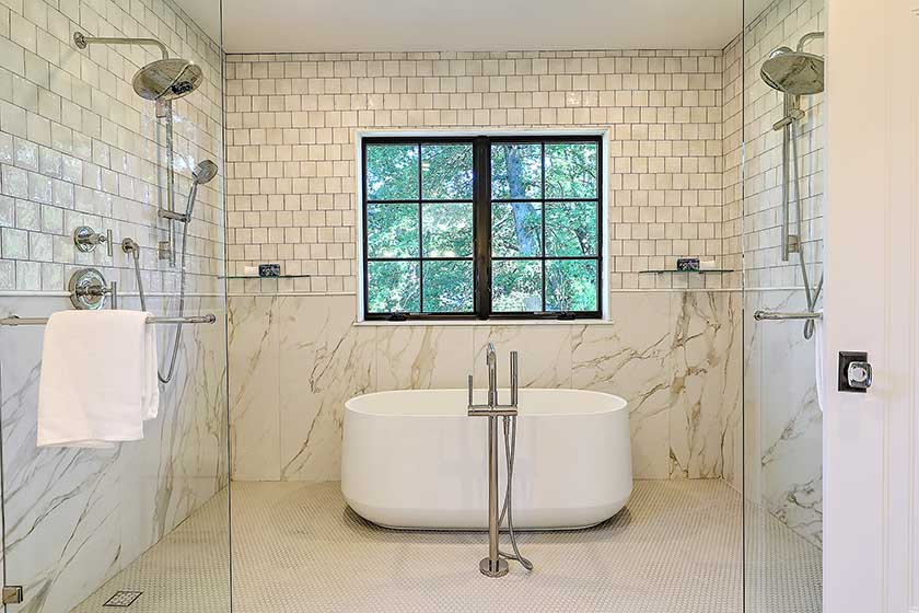 Luxury primary bathroom featuring a freestanding soaking tub and large glass-enclosed shower.