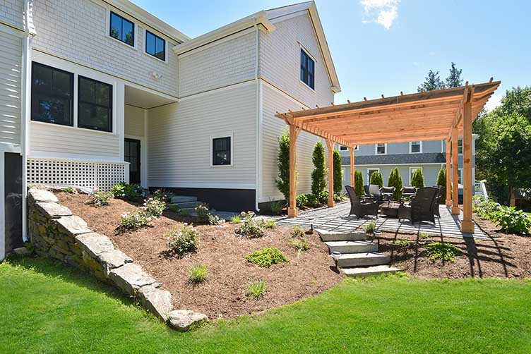 Rear exterior view of an 1870 East Greenwich home renovation, showing the seamless integration of a new addition and retaining wall.