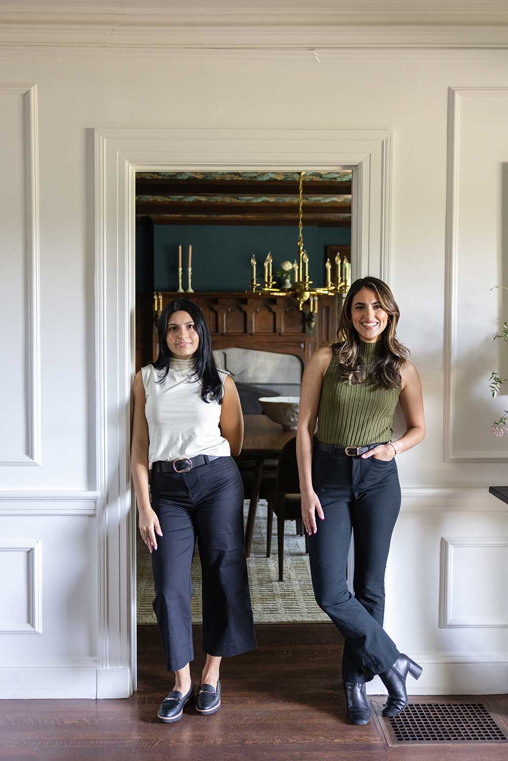 Interior designers Alissa Costello and Brianna Chace standing in a custom dining room, representing Hill & Harbor's comprehensive design development, procurement, and white-glove installation services.