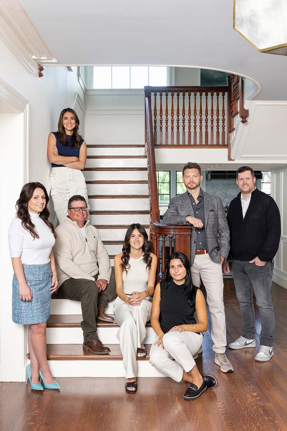 The Hill & Harbor Design Build team gathered on a staircase, representing our core values of transparency, integrity, and design-first thinking.
